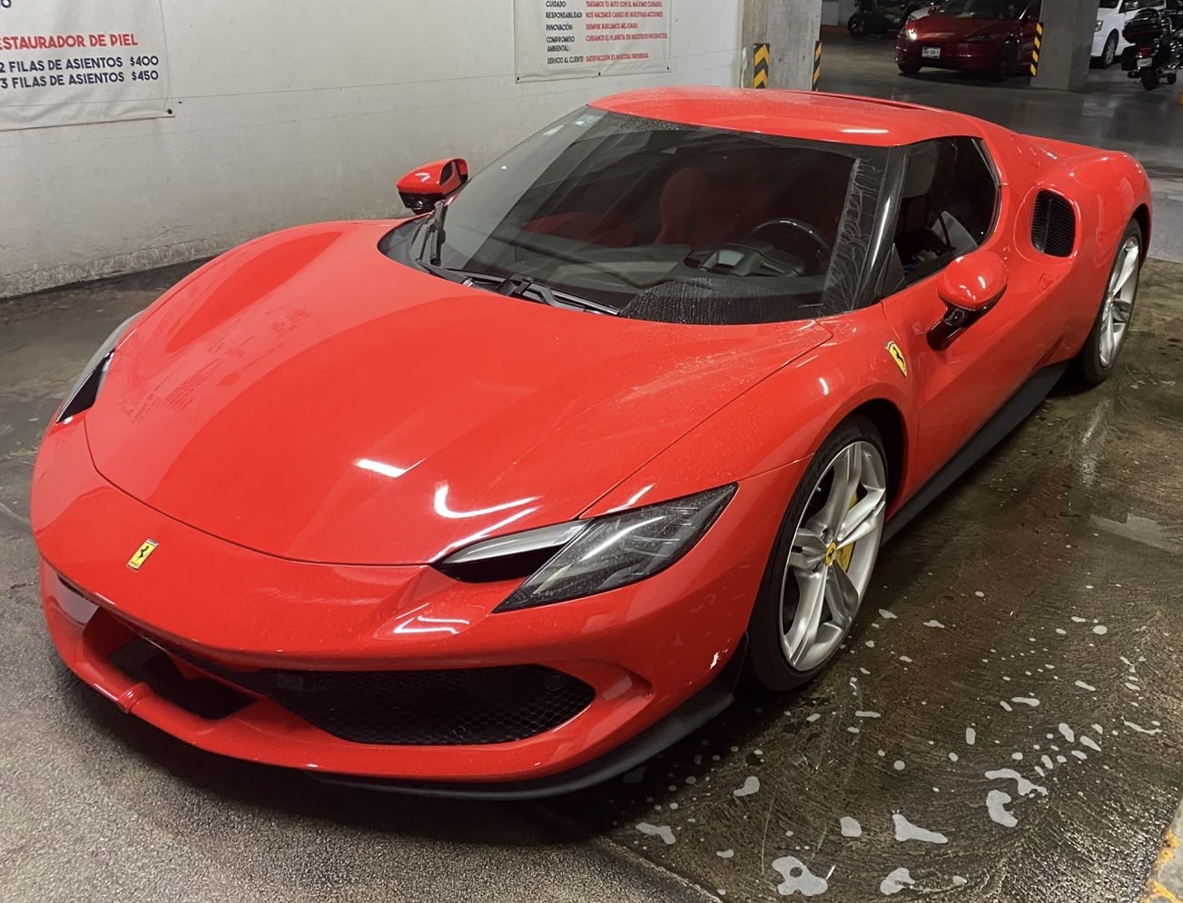 Ferrari 296 GTB rojo sobre el piso mojado con espuma de la nave de Checo Wash